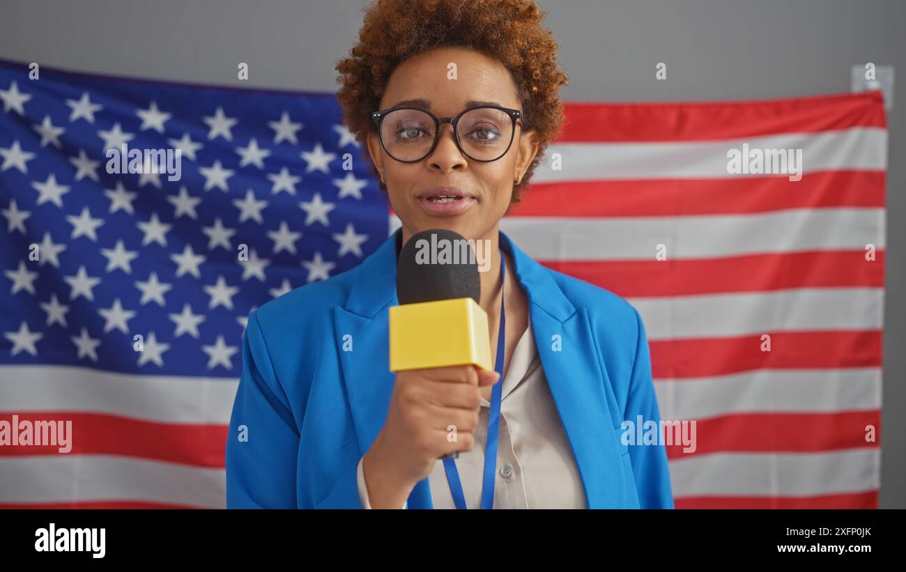 Femme afro-américaine parlant avec microphone contre nous drapeau toile de fond Banque D'Images