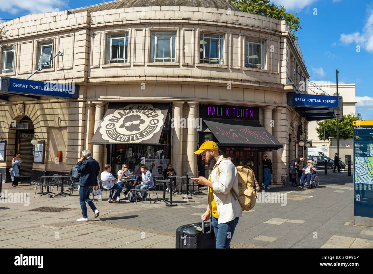 Un homme vérifiant les directions sur son téléphone à l'extérieur de la station de métro Great Portland Street Station Londres Angleterre Royaume-Uni Banque D'Images