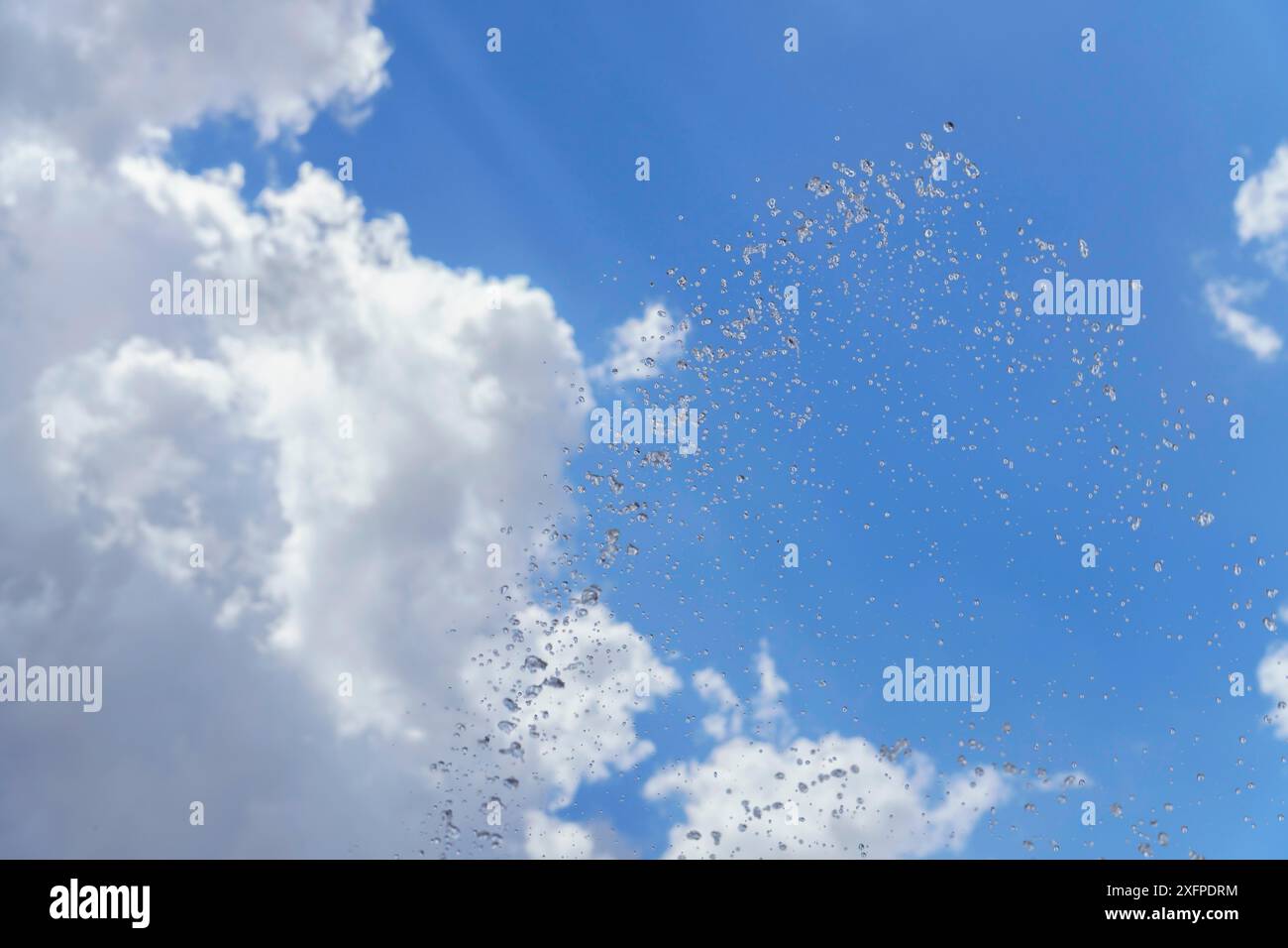 Ciel bleu nuageux avec un jet de gouttelettes d'eau flottant dans le ciel Banque D'Images