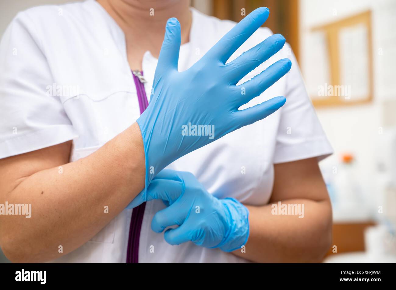 Gros plan d'une infirmière mettant des gants en latex bleu sur un fond clinique. Photo de haute qualité Banque D'Images