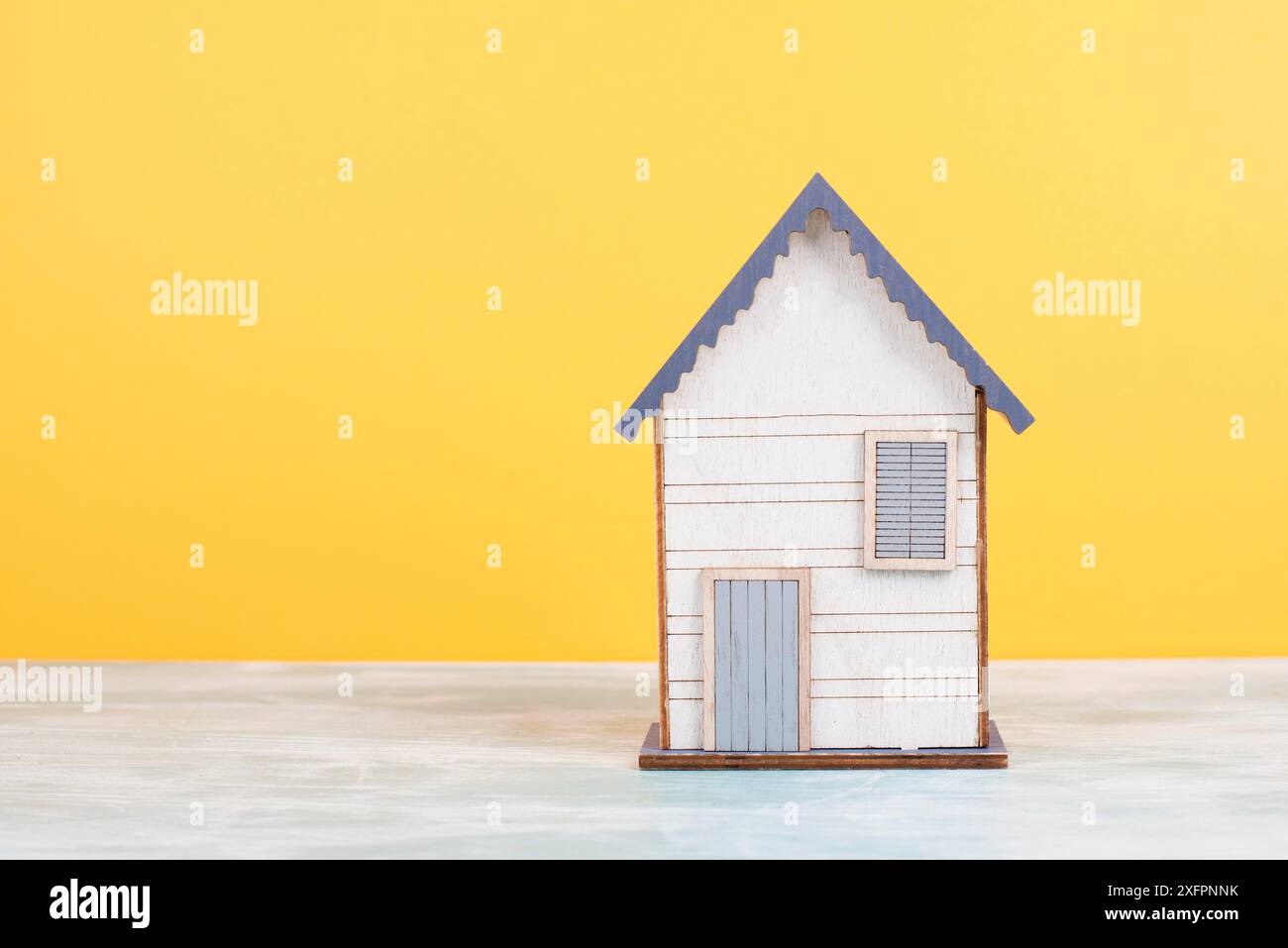 Maison en bois, fond jaune, achat ou location d'une maison, concept immobilier, réservation de maison pour vacances, propriété Banque D'Images