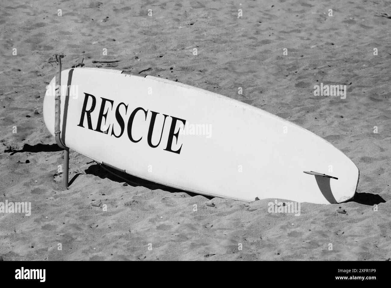 Gros plan d'une planche de surf sur le sable à la plage. Photographie noir et blanc Banque D'Images