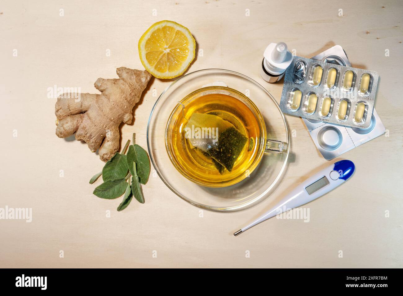 Remèdes maison et médicaments contre le rhume et la grippe tels que le thé à la sauge et au gingembre, le citron, les pilules, le spray nasal et le thermomètre de fièvre, vue de dessus, Banque D'Images