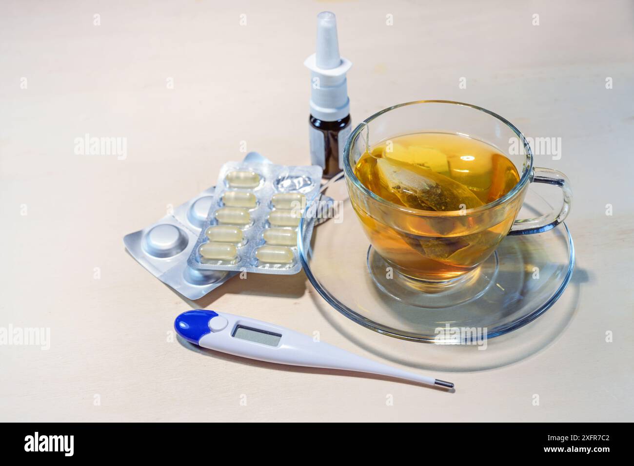 Thé chaud, pilules, spray nasal et thermomètre de fièvre, traitement médical contre le rhume et la grippe sur une table en bois, espace copie, focus sélectionné Banque D'Images