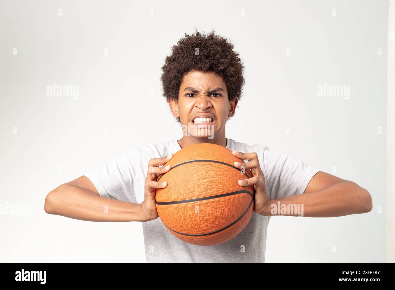 Un jeune joueur de basket-ball fait preuve d'intensité et de détermination tout en se préparant à l'action, tenant un ballon Banque D'Images