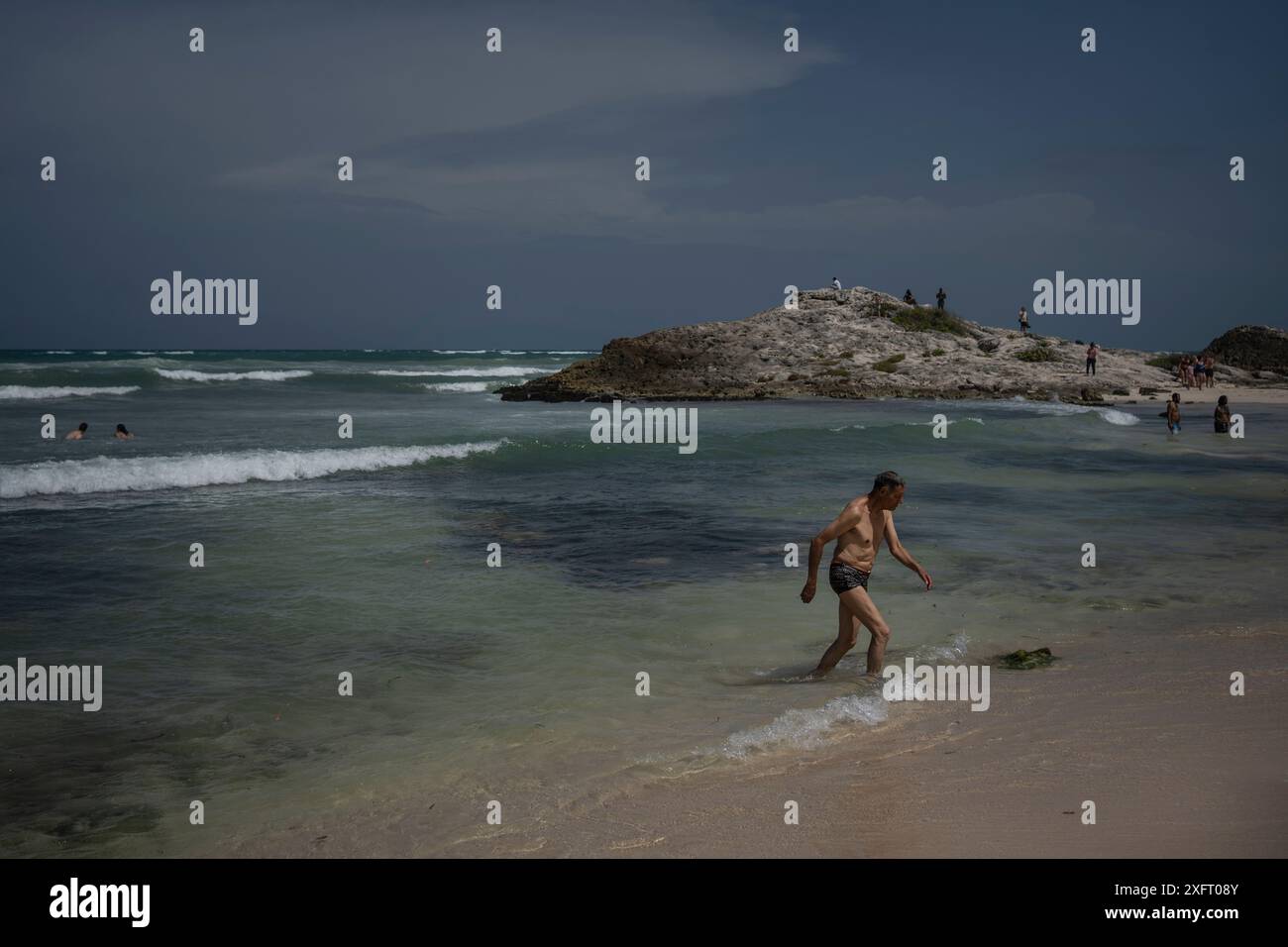 Tulum, Mexique. 04 juillet 2024. Un homme sort de la mer avant l'arrivée de l'ouragan Beryl. L’ouragan atlantique devrait atteindre la côte est de la péninsule de Yucatán avec l’ouragan force 1 vendredi soir. Les experts s'attendent à de forts vents et des précipitations ainsi qu'à de dangereuses ondes de tempête. Crédit : Felix Marquez/dpa/Alamy Live News Banque D'Images