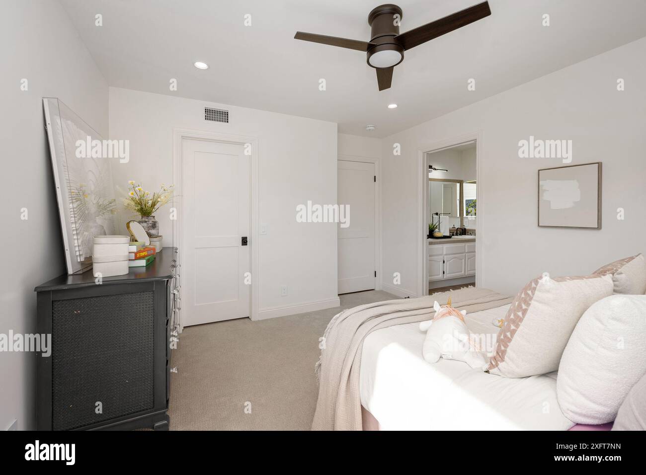 L''intérieur moderne de la chambre comprend des murs beiges, un ventilateur de plafond et une vue sur une salle de bains Banque D'Images