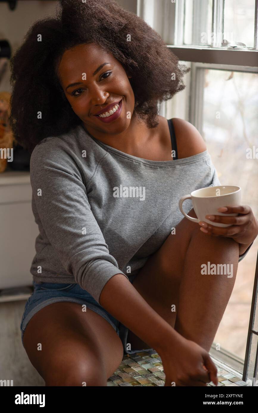 Souriant à la caméra tenant le café Banque D'Images