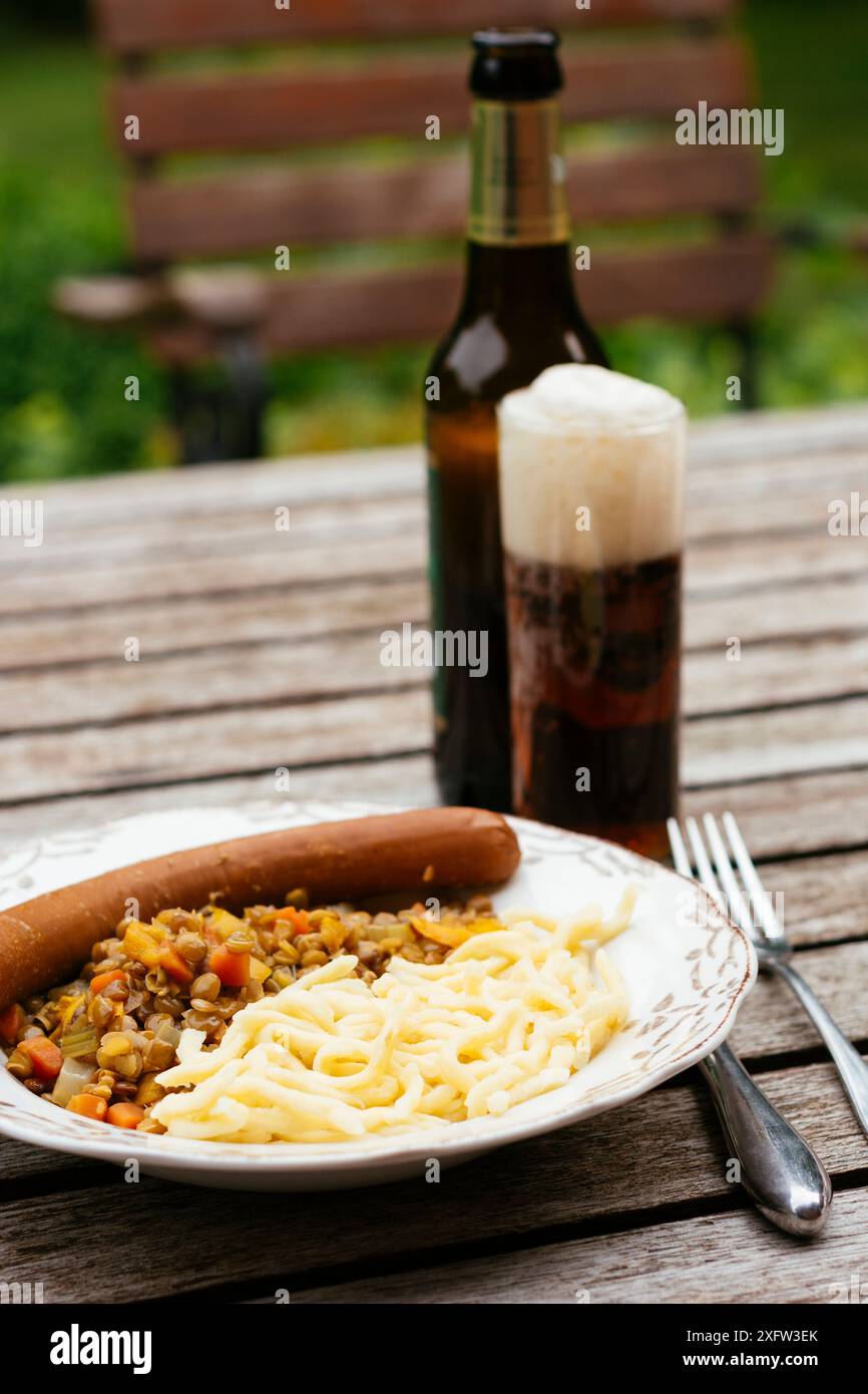 Ragoût de lentilles avec carottes, oignons et céleri, servi avec du Spätzle et une saucisse végétalienne. Banque D'Images