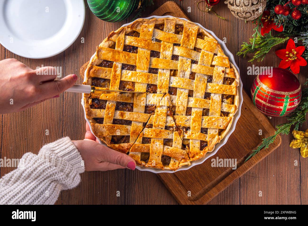 Tarte de Noël britannique traditionnelle. Gâteau à la tarte au mincemeat sucré maison, rempli de fruits secs épicés, de noix et de pommes, sur une table en bois confortable Wit Banque D'Images