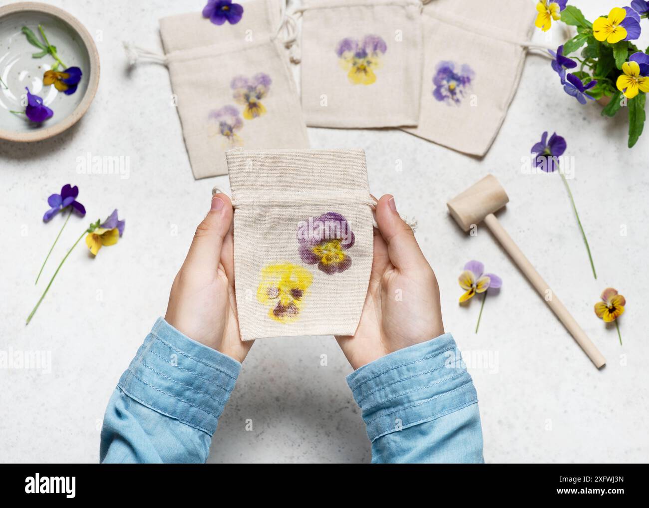 Vue d'en haut d'un petit sac en tissu fait à la main avec des impressions de fleurs martelées de pensées. Étape par étape de la création d'un sac en tissu avec des imprimés de fleurs. Banque D'Images