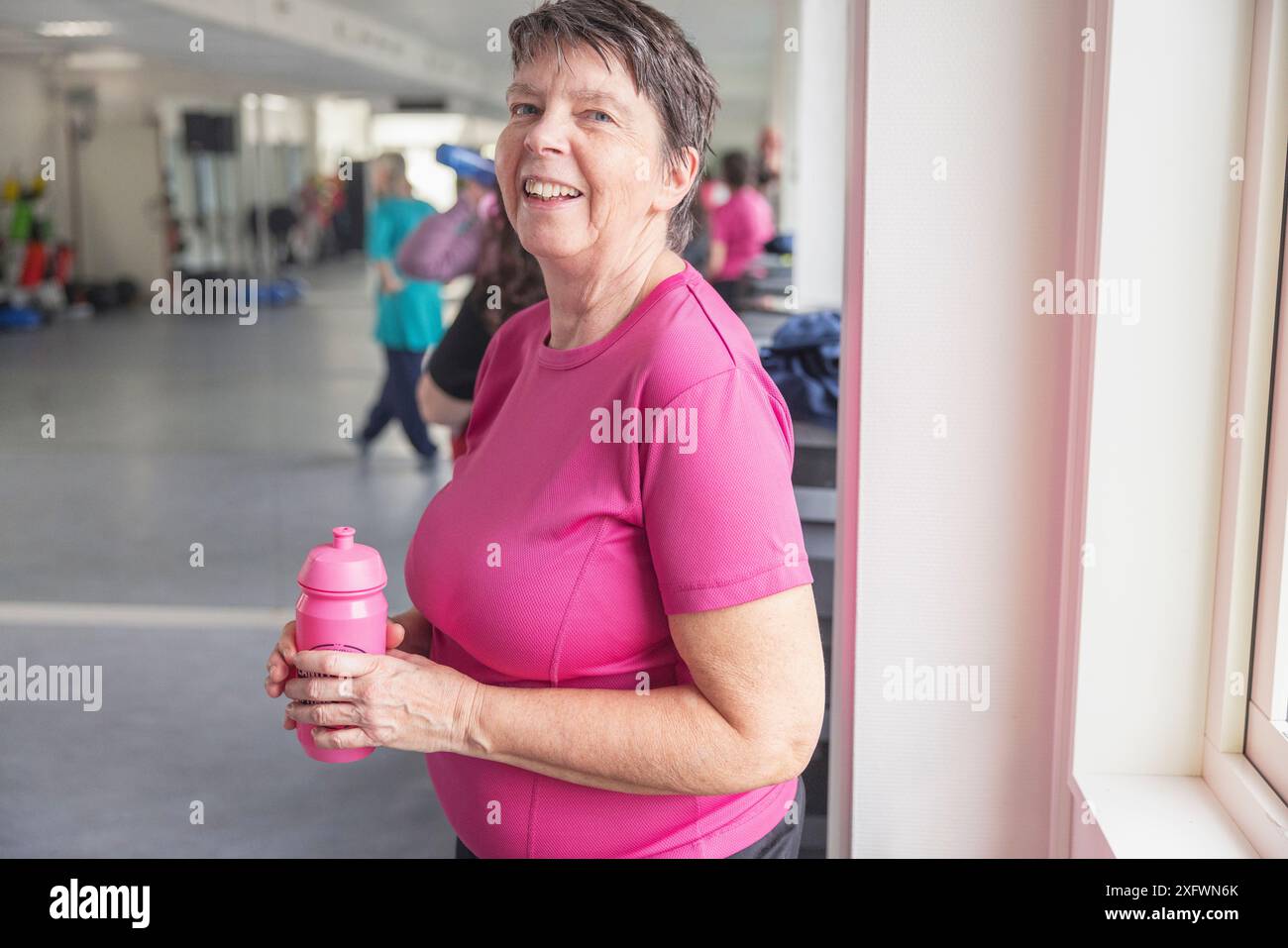 Portrait de femme mature heureuse avec bouteille d'eau au studio de danse Banque D'Images