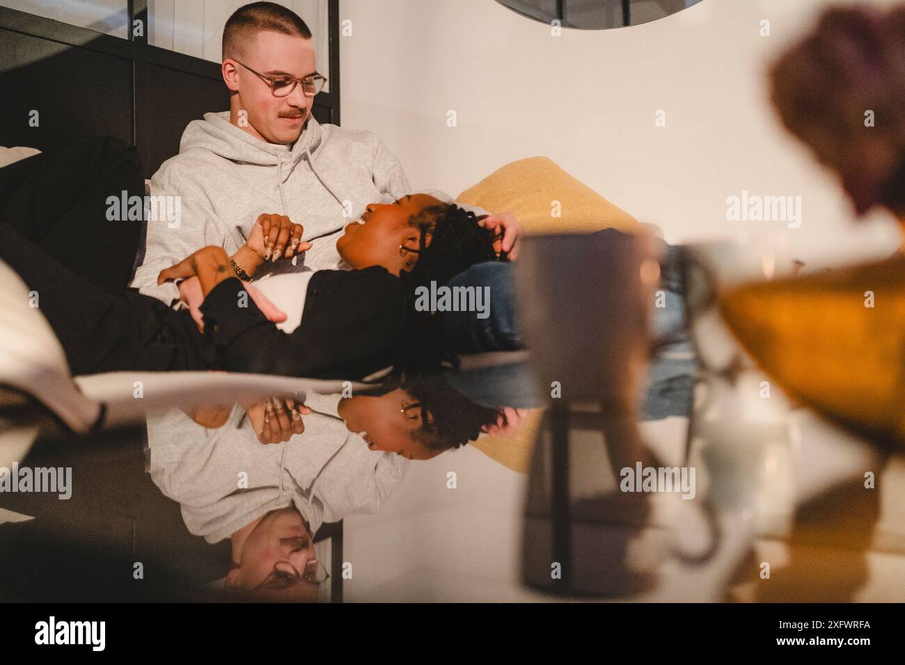 Couple multiracial souriant passant du temps libre à parler à la maison Banque D'Images