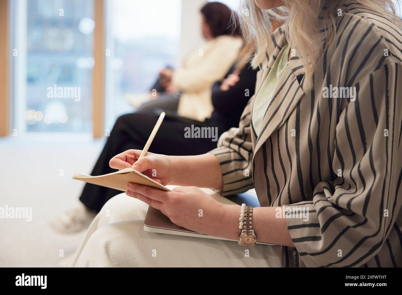 Milieu de section d'une jeune femme d'affaires prenant des notes lors de la réunion au bureau Banque D'Images