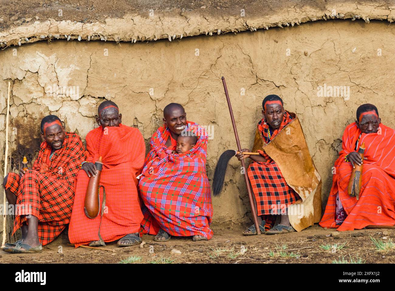 Les anciens du village Maasai, un avec bébé. Avec des armes à boire devant la cabane, village Maasai, Kenya. Septembre 2006. Banque D'Images