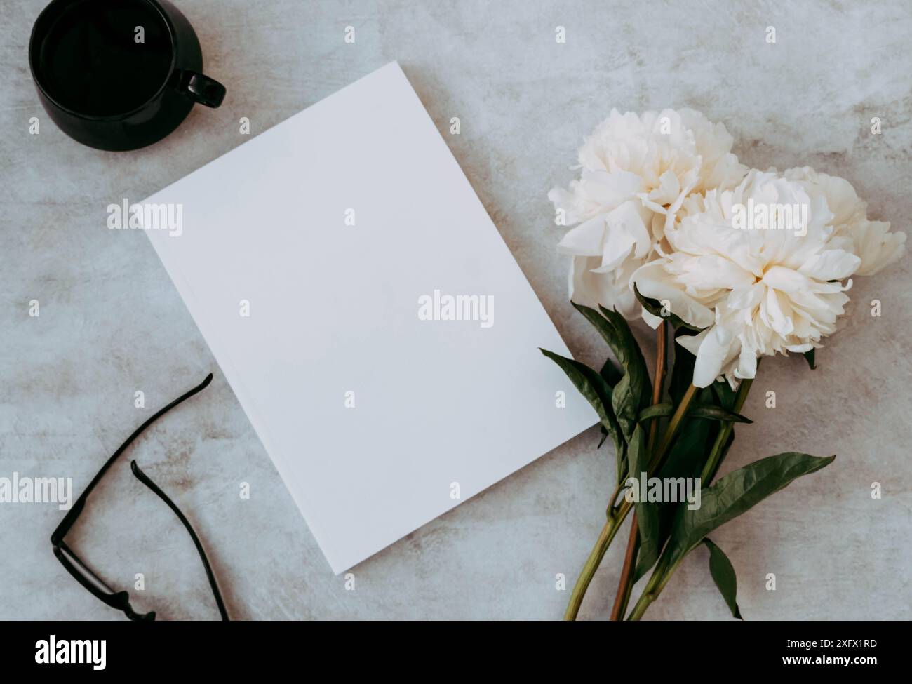 Bouquet de fleurs de pivoine blanche, maquette vide blanche de couverture de magazine, tasse de thé et lunettes noires sur table grise. Vue de dessus. Copier l'espace. Plat la Banque D'Images