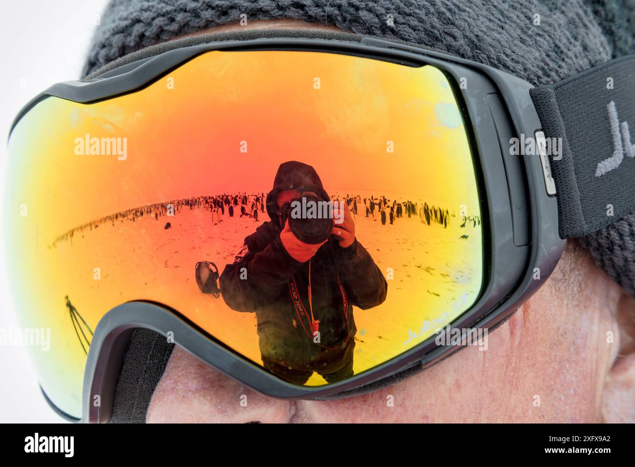 Photographe Sue Flood prenant une photo d'elle-même et de la colonie du manchot empereur (Aptenodytes forsteri) en reflétant les lunettes de quelqu'un, baie de Gould, mer de Weddell, Antarctique. Banque D'Images