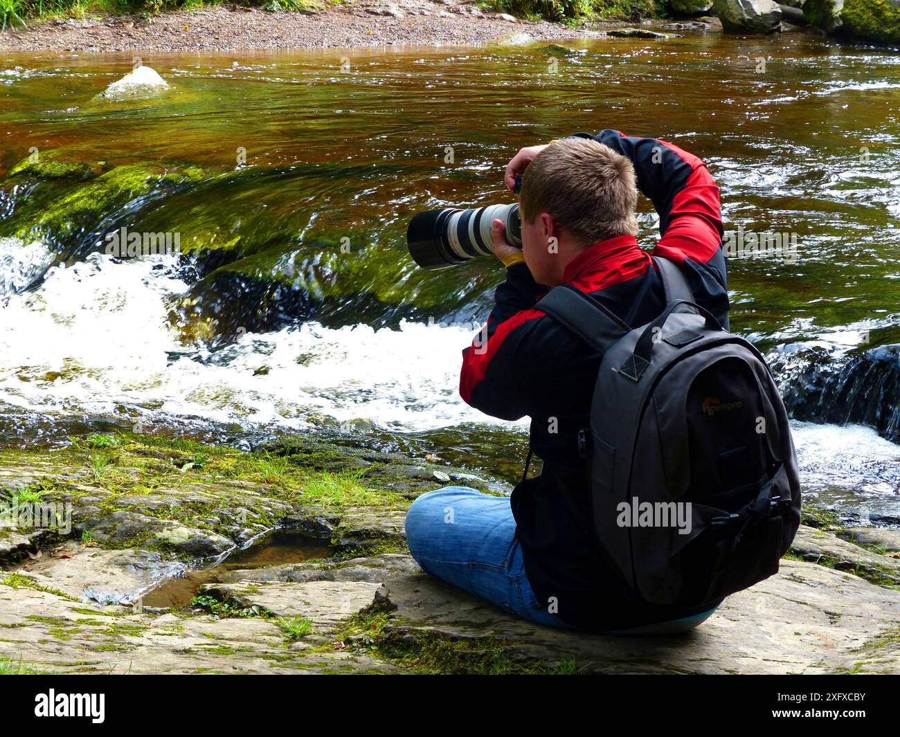 Oliver Hellowell prenant des photos du ruisseau Dartmoor, Devon, Angleterre, Royaume-Uni, août. Banque D'Images