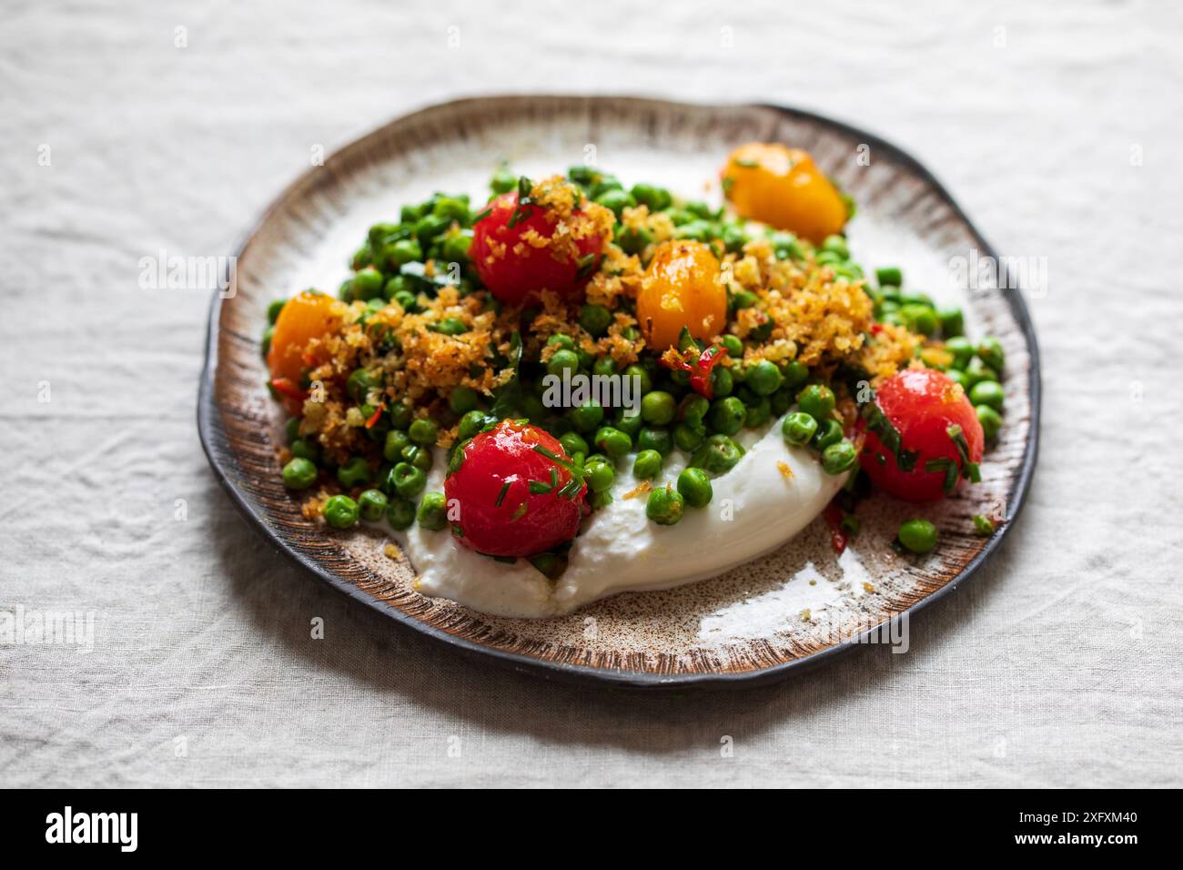 Burrata avec petits pois grillés, tomates marinées et chapelure Banque D'Images