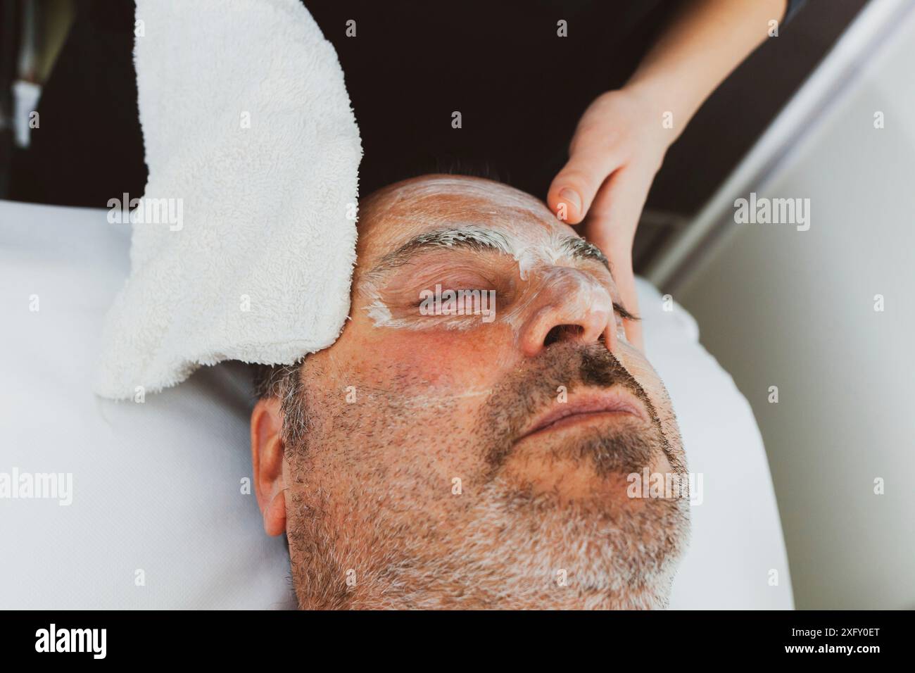 Homme d'âge moyen dans un salon de beauté avec un masque facial. Banque D'Images