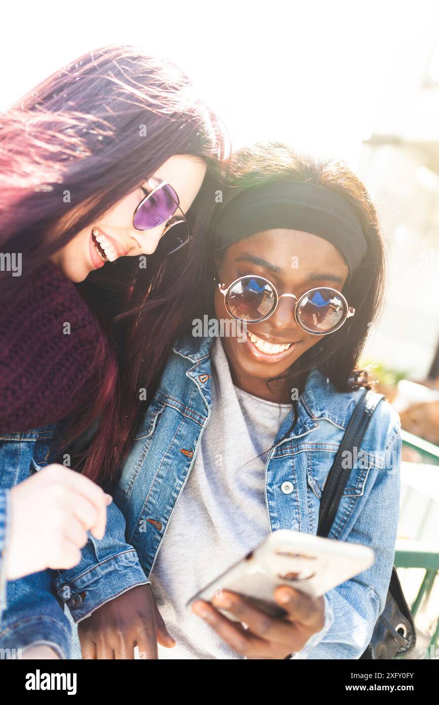 Avoir du plaisir avec vos amis multiraciale smartphone dans une journée de printemps. Banque D'Images