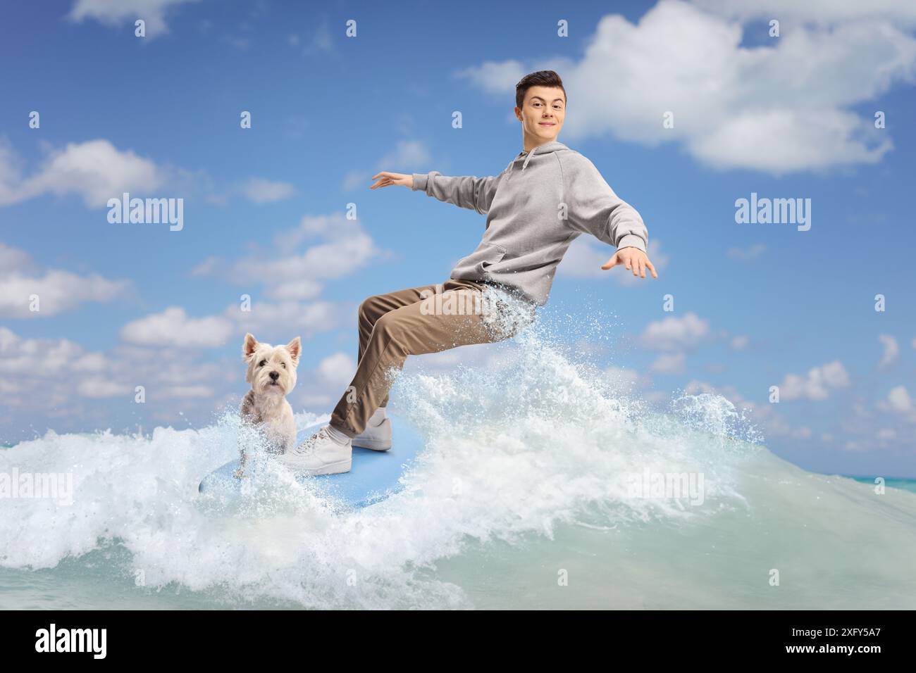 Adolescent mâle avec un chien surfant sur une vague dans la mer Banque D'Images