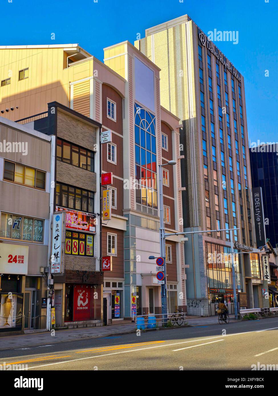 Des bâtiments étroits multicolores bordent la rue de Fukuoka. Ancien port, Fukuoka est aujourd’hui un centre commercial, industriel, administratif et culturel régional. La ville contient un port de pêche actif et dispose de nombreuses liaisons ferroviaires et routières avec Kitakyūshū et avec les villes le long de la partie ouest de Kyushu, y compris une branche du Shinkansen (train à grande vitesse). Japon. Banque D'Images