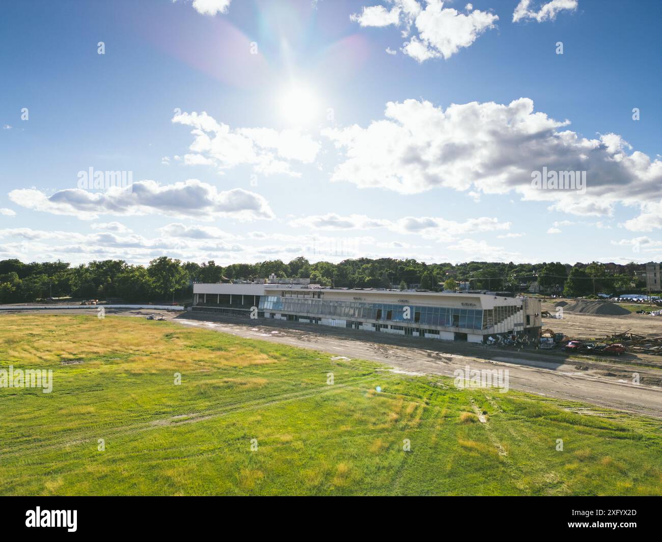 Un champ vert avec un vieux bâtiment par un chantier de construction et des machines Banque D'Images