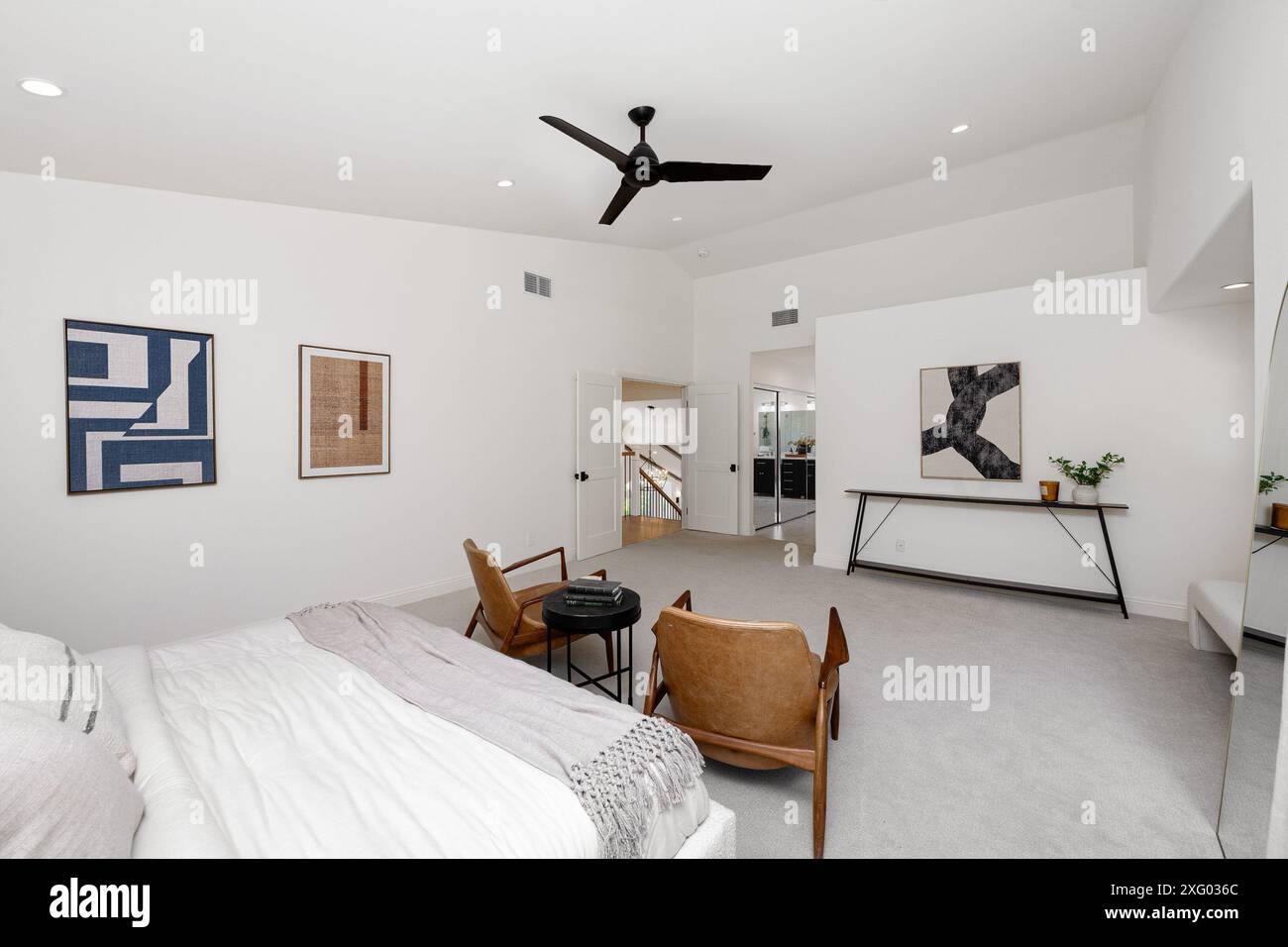 Cette chambre moderne à la décoration minimaliste est dotée d''un ventilateur de plafond, d''œuvres d''art et d''un coin salon confortable. Banque D'Images