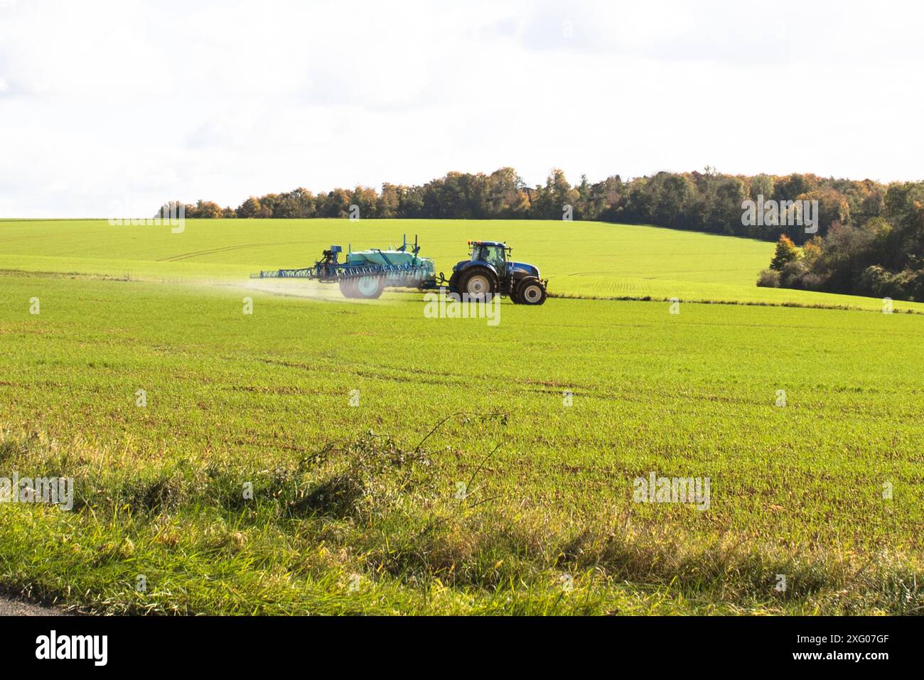 Agriculteur avec pulvérisateur traîné, traitant les cultures d'orge contre les pucerons qui transmettent les virus nains jaunes de l'orge, et désherbant contre l'herbe et les feuilles larges w Banque D'Images