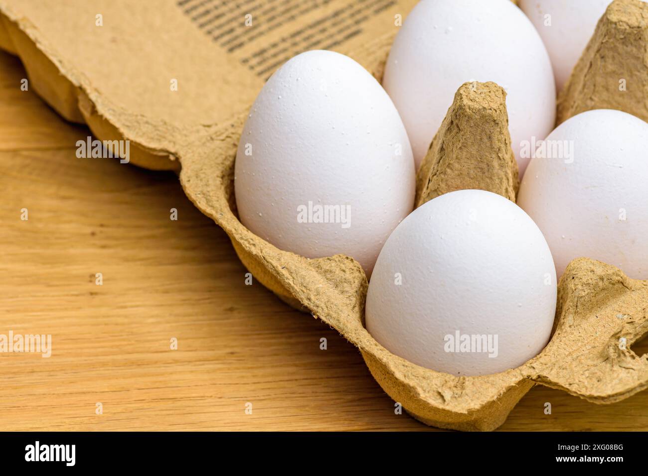 Gros plan d'œufs de poules élevées en liberté dans un carton d'oeufs sur un fond en bois Banque D'Images