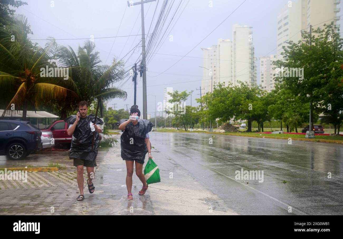 Cancun, Mexique. 5 juillet 2024. Les gens marchent sous la pluie après la chute de l'ouragan Beryl, à Cancun, dans l'état de Quintana Roo, au Mexique, le 5 juillet, 2024. dans les Caraïbes, plus d'un million de personnes ont été touchées par l'ouragan Beryl, ont déclaré vendredi les humanitaires des Nations Unies. Ouragan de catégorie 4 qui a fait au moins 11 morts à ce jour, Beryl a laissé lundi une traînée de destruction à Grenade et Saint-Vincent-et-les Grenadines, puis a touché la Jamaïque mercredi. L'ouragan affecte actuellement le Belize et le Mexique. Crédit : Alberto Valdez/Xinhua/Alamy Live News Banque D'Images