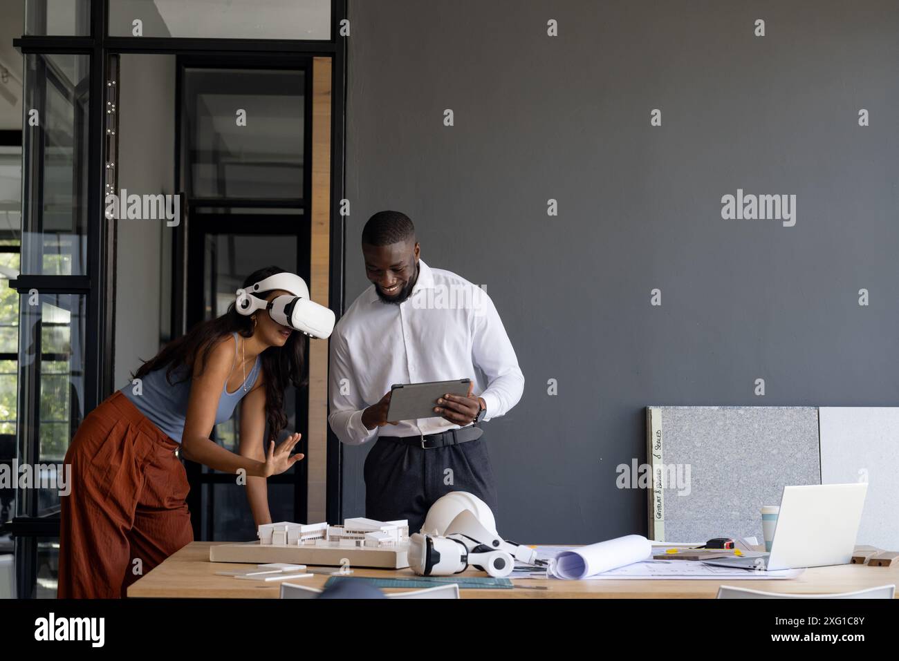 En utilisant un casque VR, femme collaborant avec un homme tenant une tablette dans un bureau moderne, espace de copie Banque D'Images