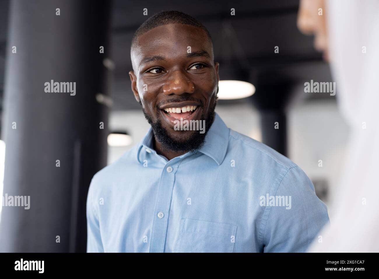 Homme d'affaires souriant dans la chemise bleue s'engageant dans la conversation au bureau Banque D'Images
