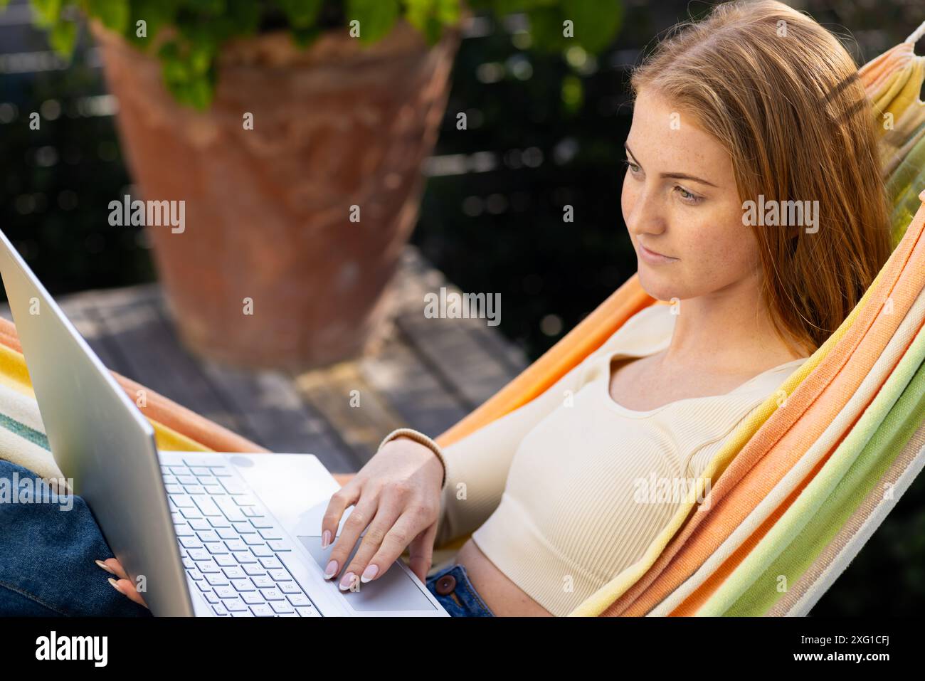 Détente dans un hamac, femme utilisant un ordinateur portable pour le travail ou les loisirs à l'extérieur Banque D'Images