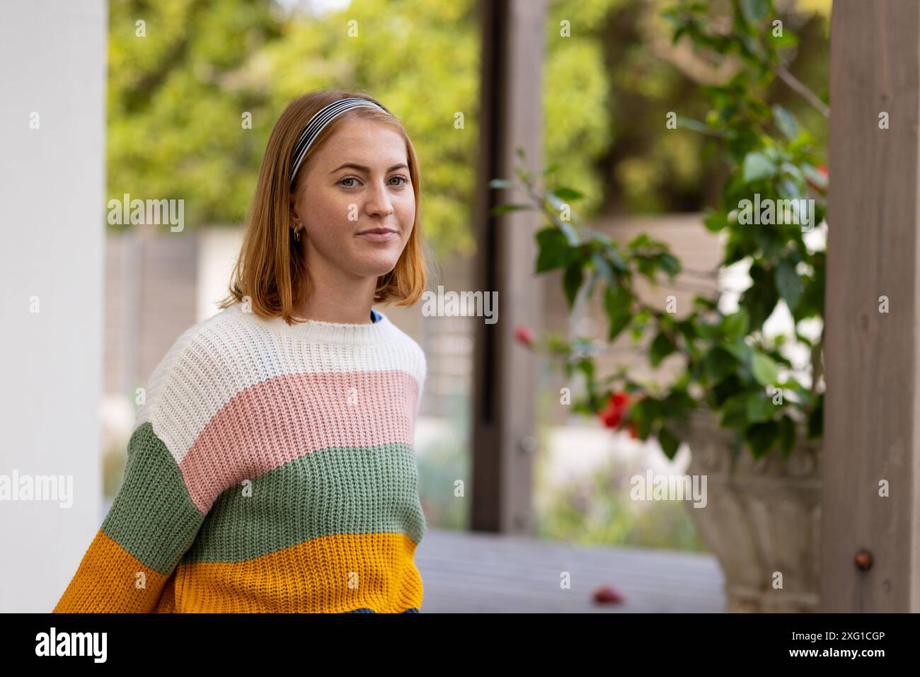 Femme en pull coloré debout à l'extérieur de la maison, regardant la caméra, l'espace de copie Banque D'Images