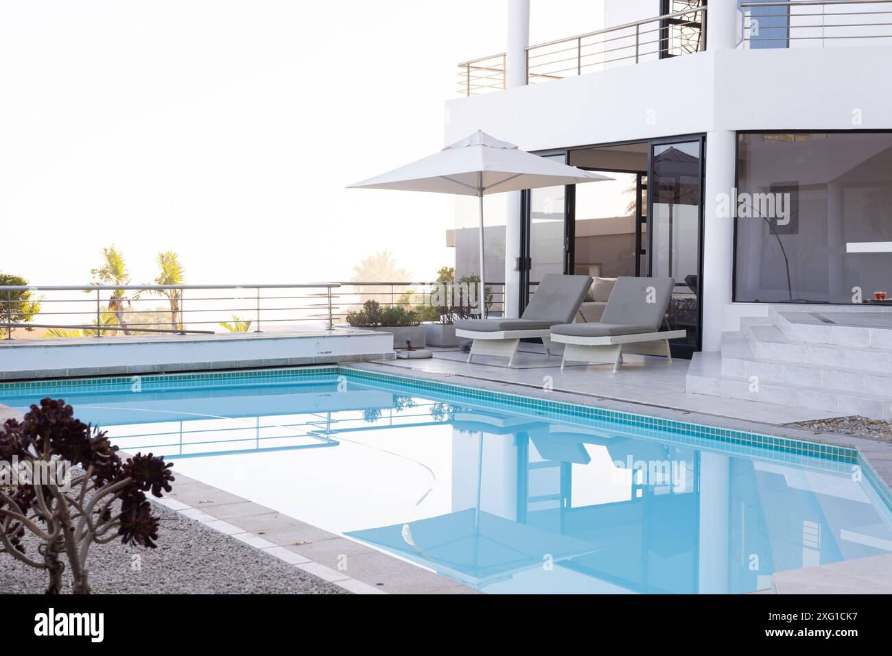 Vacances de luxe, chaises longues au bord de la piscine et parasol par villa moderne, espace photocopie Banque D'Images