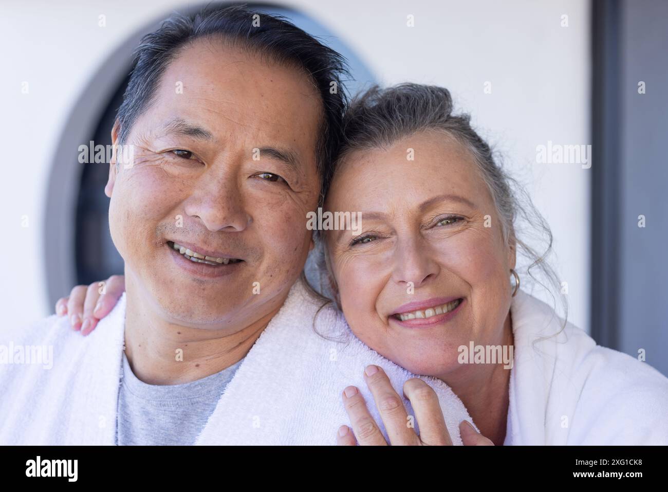 Couple senior souriant profitant de vacances, embrassant et regardant la caméra Banque D'Images