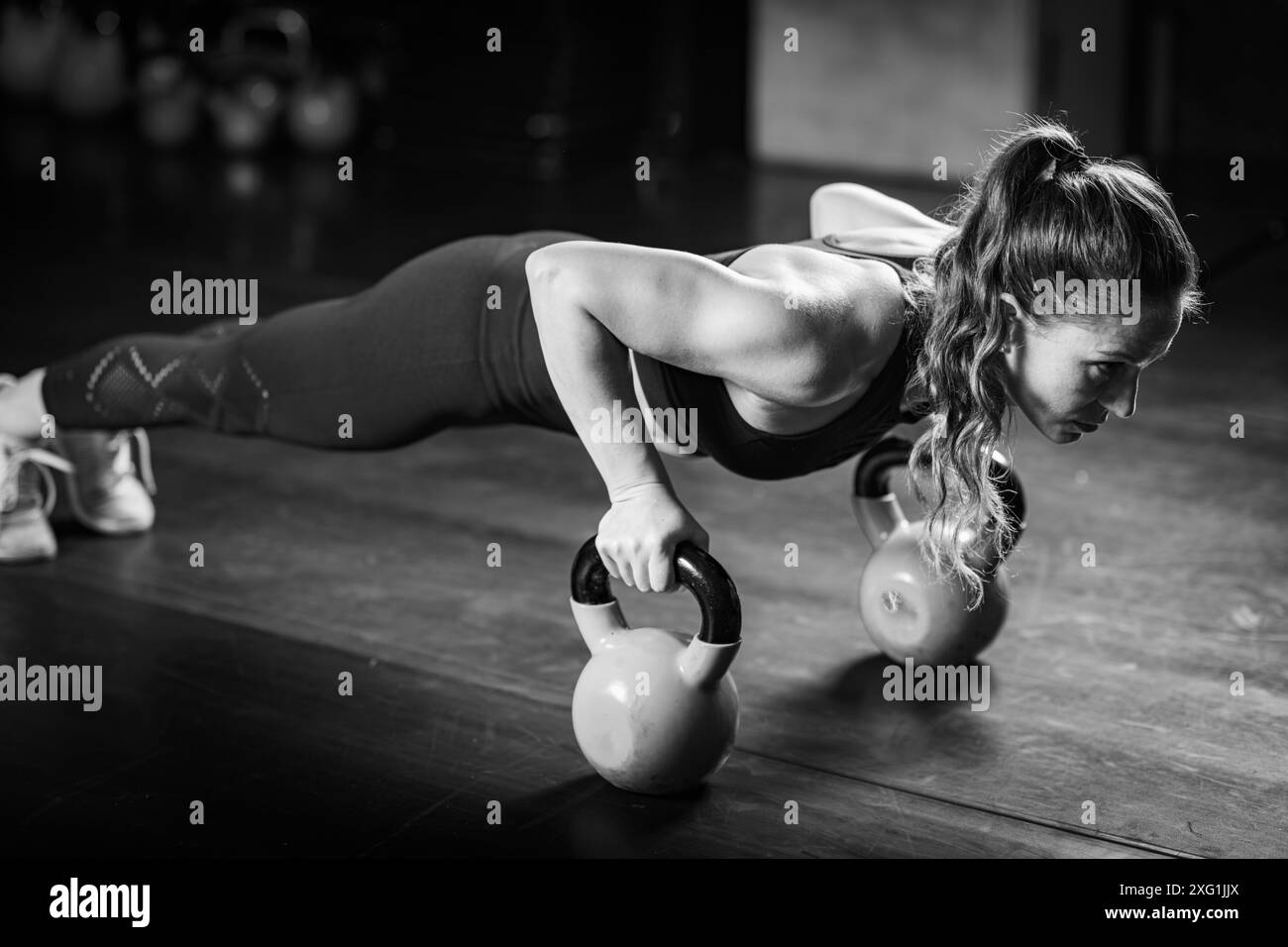 Femme faisant des pompes avec des kettlebells. Banque D'Images