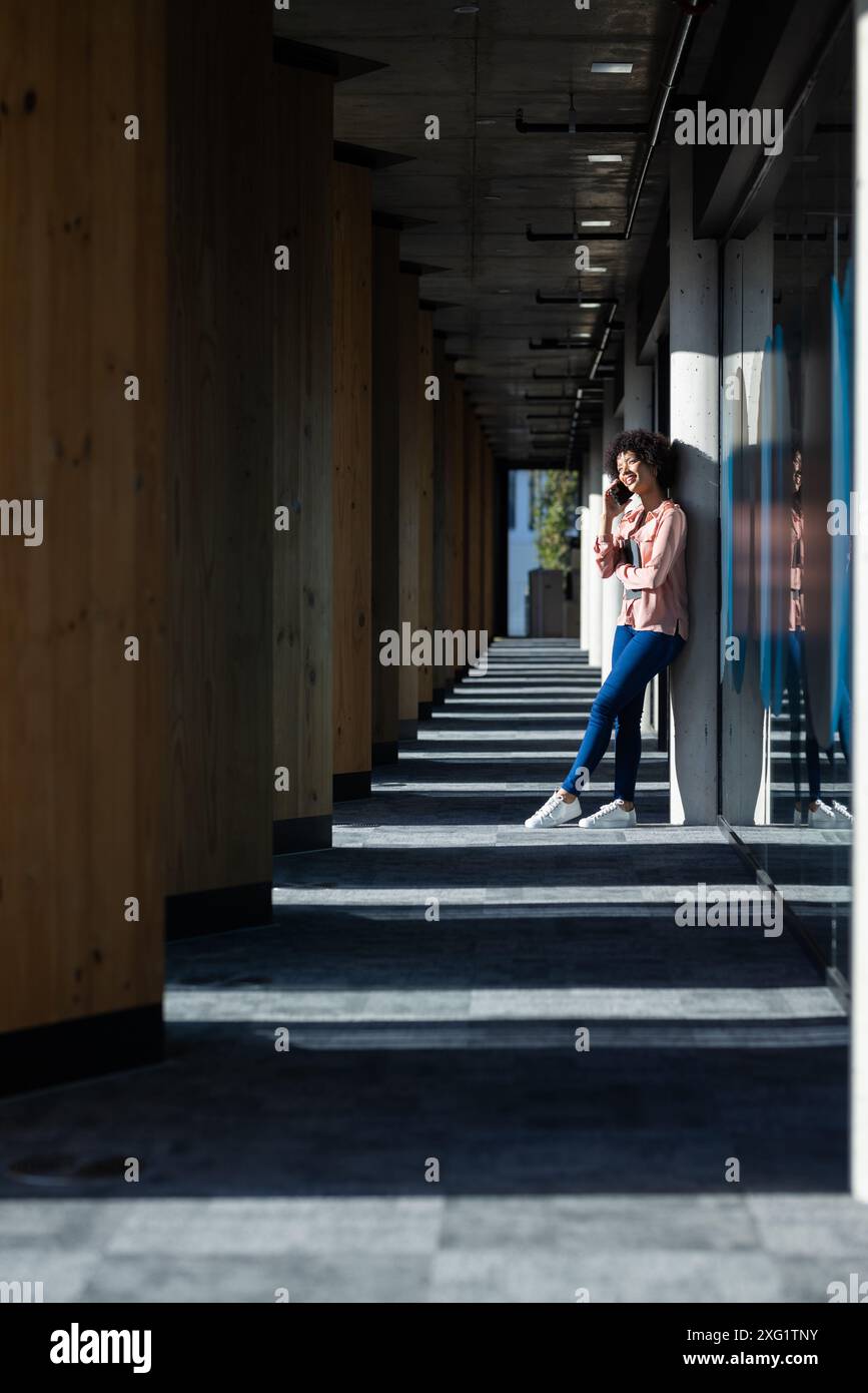 Debout dans le couloir, femme buvant du café et utilisant un smartphone, profitant de la pause, espace de copie Banque D'Images
