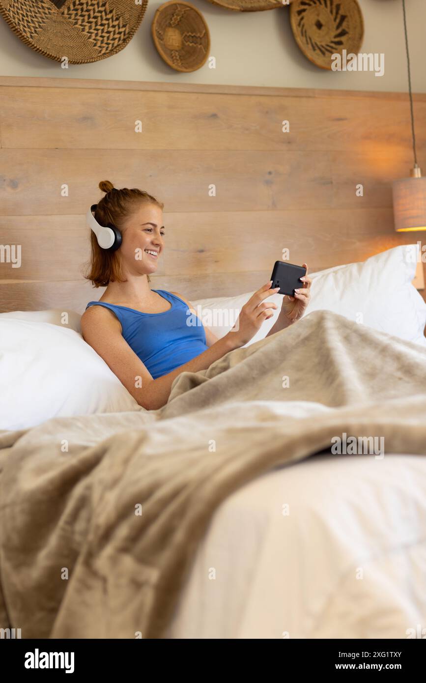 Port d'écouteurs, femme se relaxant dans le lit et regardant la vidéo sur smartphone, espace de copie Banque D'Images
