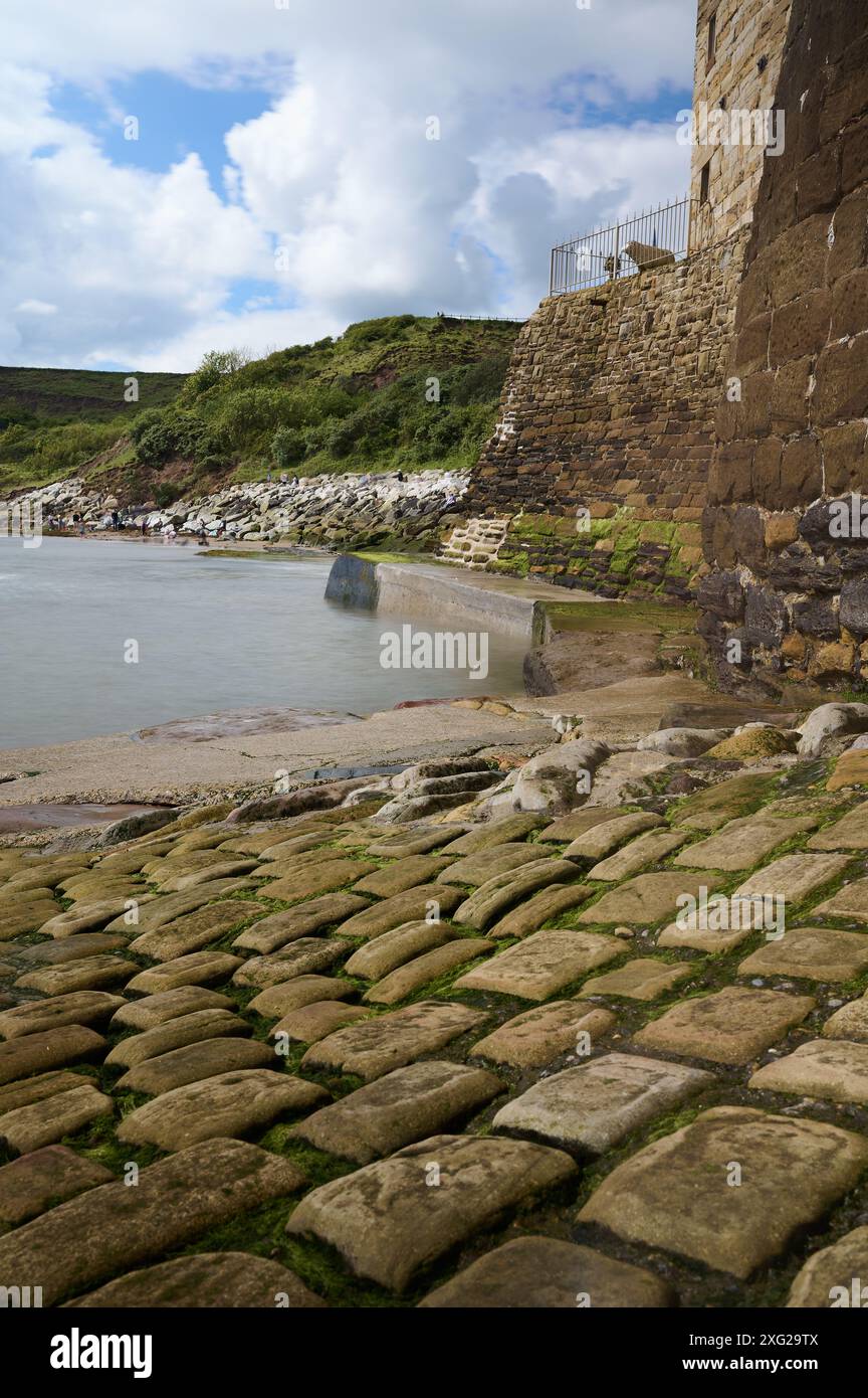 Vue basse de la cale pavée dans la mer à robin Hoops Bay dans le yorkshire en utilisant une longue exposition pour brouiller le mouvement des vagues Banque D'Images