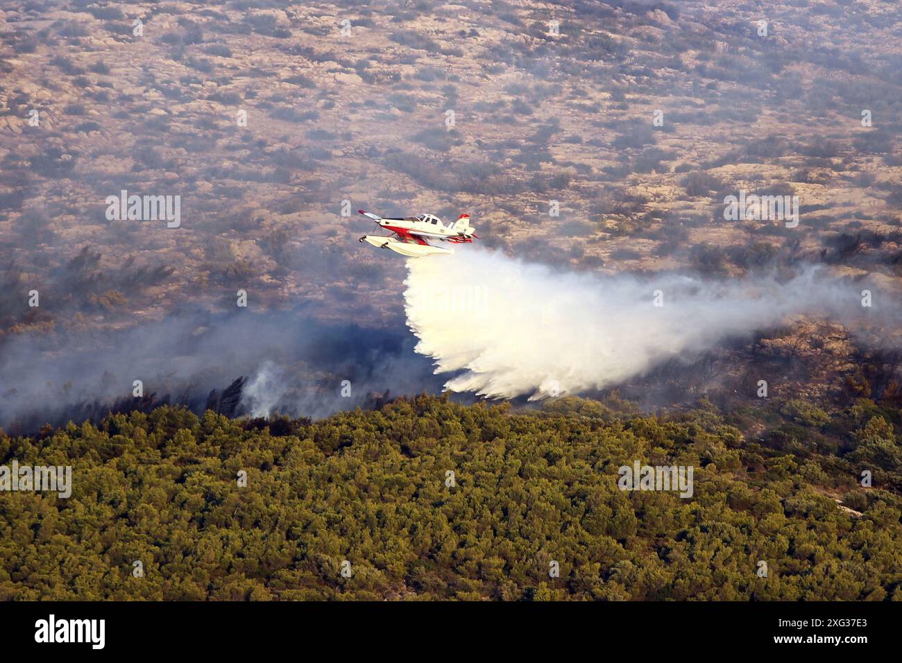 Un hélicoptère de lutte contre l'incendie jette de l'eau au-dessus d'un feu de forêt dans la région de Keratea, au sud-est d'Athènes. Banque D'Images