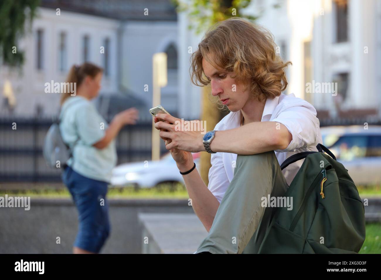 Guy utilisant un smartphone dans la rue de la ville en été Banque D'Images