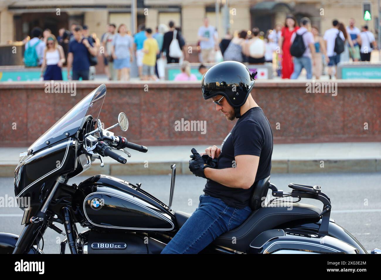 Homme sur la moto arrêté et en utilisant smartphone sur la rue de la ville Banque D'Images
