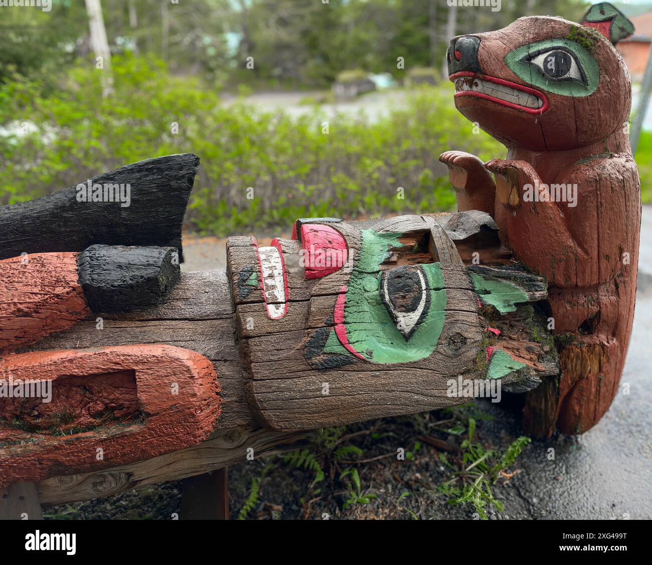 Le totem en Alaska a besoin d'être réparé. La statue sculptée repose sur le sol en position horizontale. Des parties du bois ont pourri et la peinture est écaillée. Banque D'Images