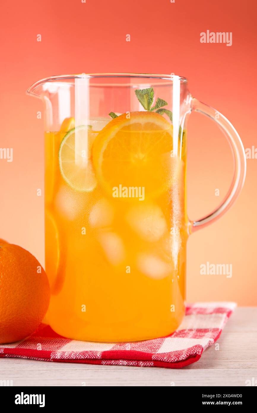 Limonade fraîchement préparée dans une cruche et orange sur une table en bois clair Banque D'Images