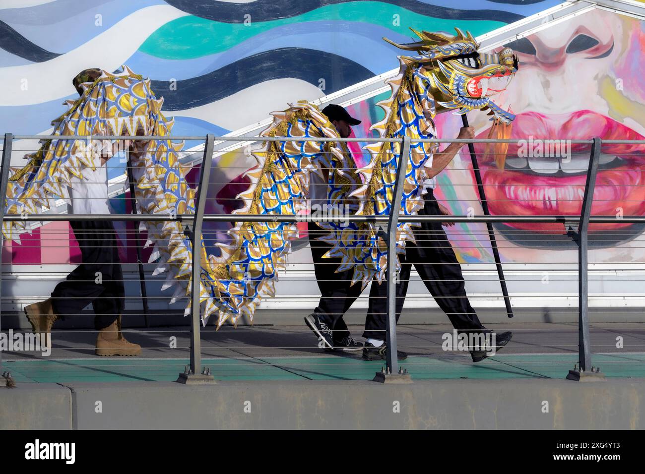 Des artistes portant une marionnette de dragon chinois traditionnelle avec une fresque colorée en arrière-plan de la défilé du Stampede de Calgary Banque D'Images