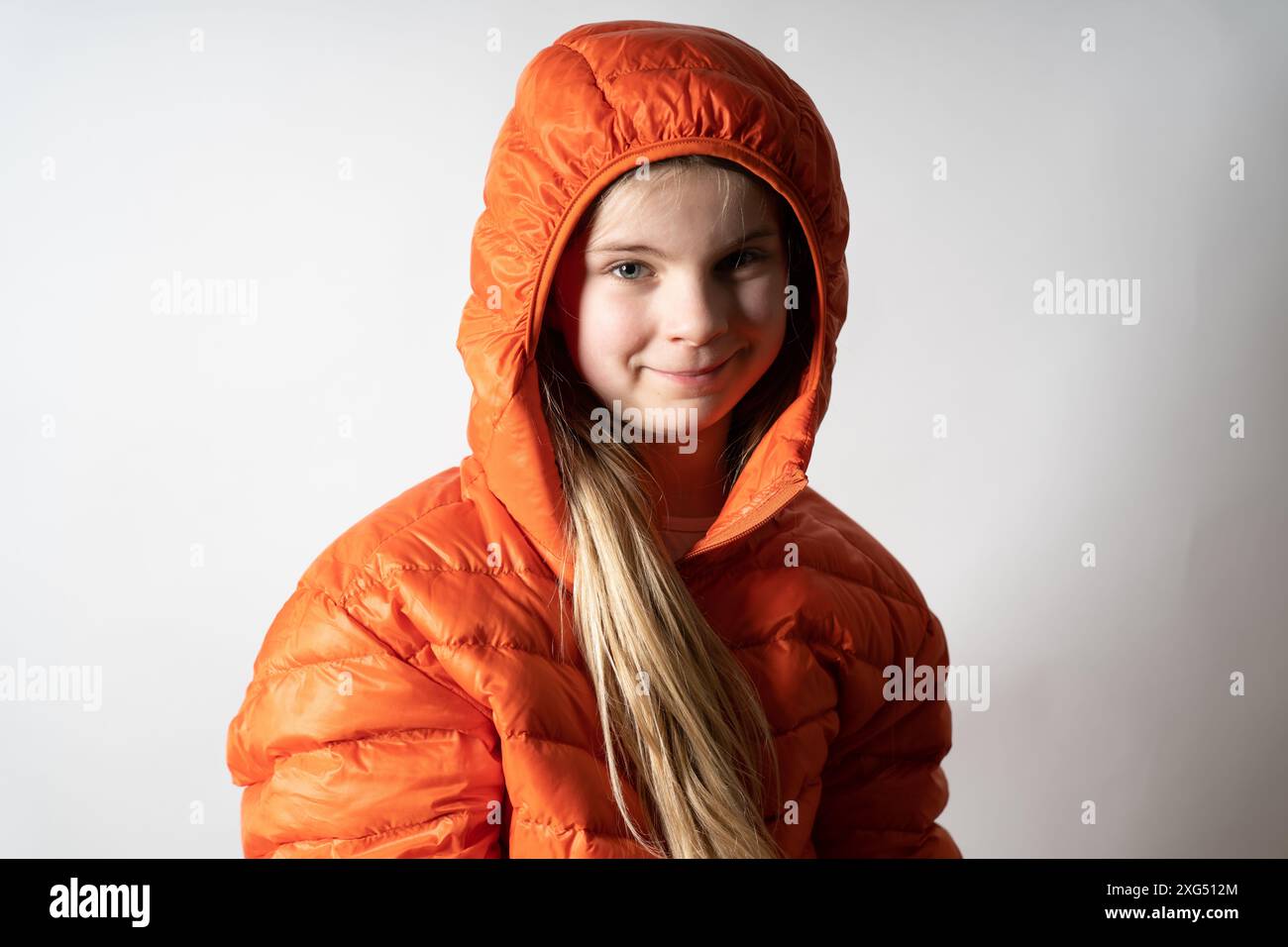 Jeune jolie fille dans un studio photo portrait comme modèle. Elle se sent à l'aise et en sécurité dans sa veste rouge. Bientôt, elle joue avec d'autres enfants. Banque D'Images