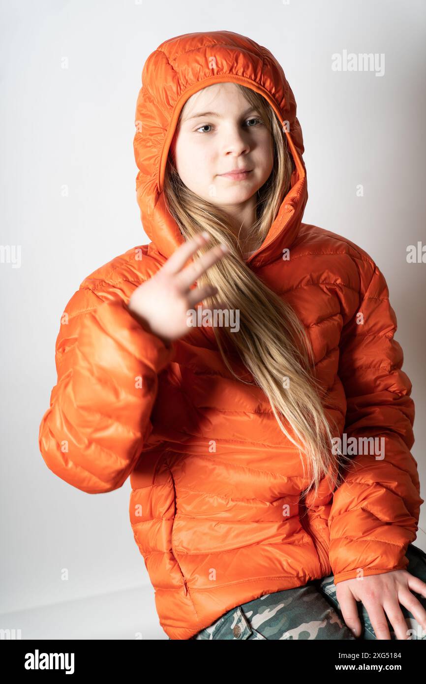 Jeune jolie fille dans un studio photo portrait comme modèle. Elle se sent à l'aise et en sécurité dans sa veste rouge. Bientôt, elle joue avec d'autres enfants. Banque D'Images